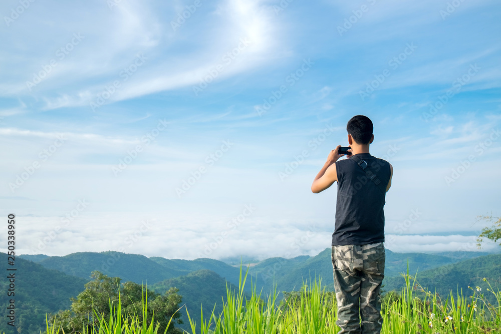 Teenager Tourist Take a Photo of Landscape Mountain Hill Fog from Top of the Mountain with His Smartphone Teenager Tourist Take a Photo of Landscape Mountain Hill Fog from Top of the Mountain with His Smartphone