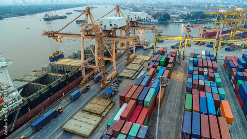 Logistics and transportation of Container Cargo ship and Cargo plane with working crane bridge in shipyard at sunrise, logistic import export and transport industry background