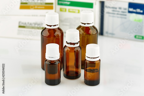 Five small brown medicine phials with pills packs on background.