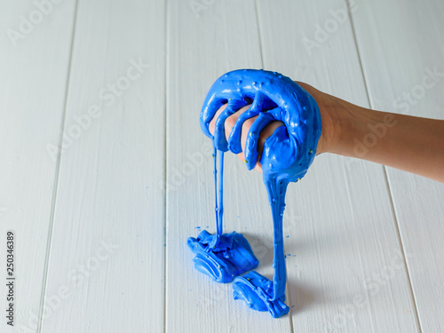 The blue slime flows from the child's right hand onto the white table. photo