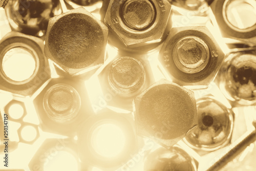 Art monochrome background from bolts and nuts close up in blue backlight. Small fasteners in macro in sepia tones.
