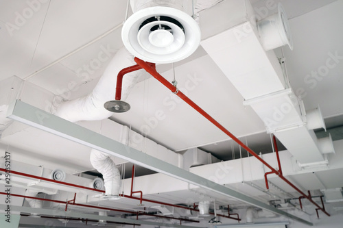 Perspective view of white air duct on the ceiling with red water sprinkler pipe