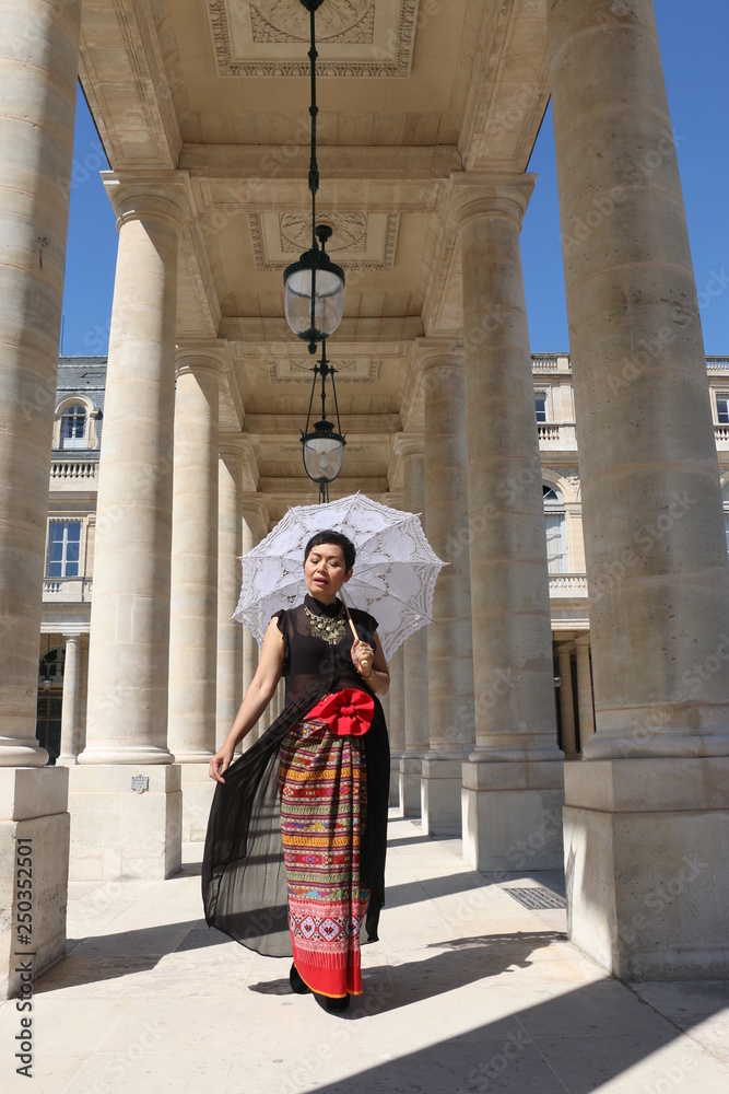 Femme avec ombrelle blanche en dentelle sous un portique du palais royal