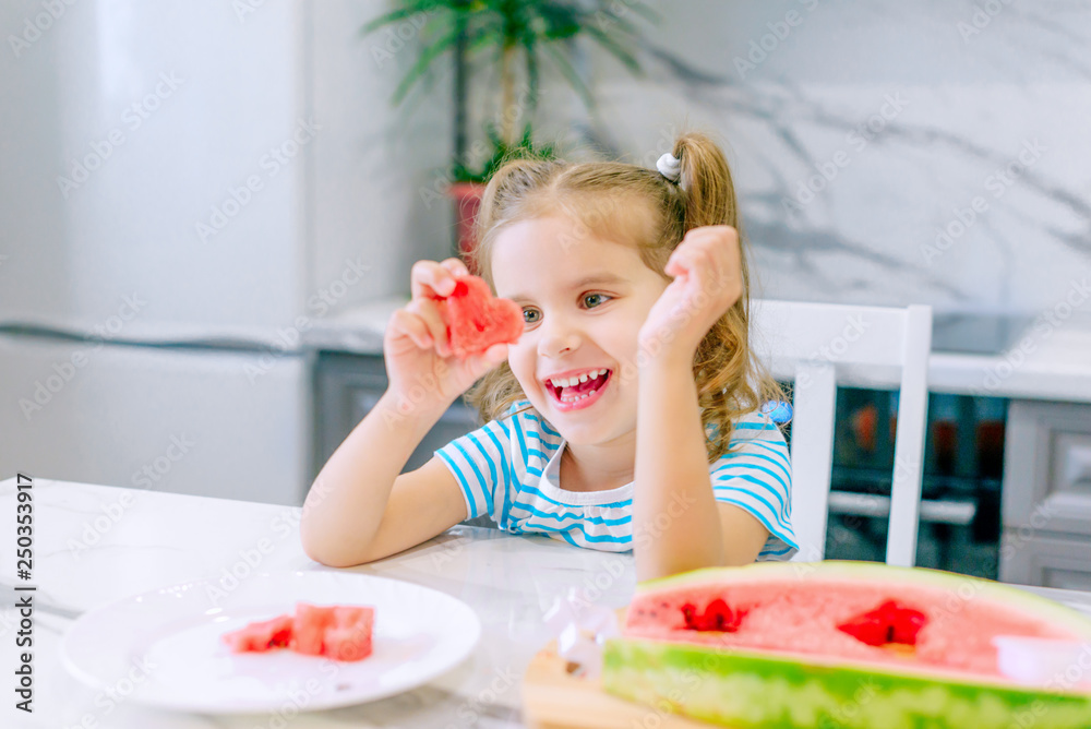 Happy baby girl eating watermelon in the kitchen. Baby food concept. Happy baby girl eating watermelon in the kitchen. Baby food concept.