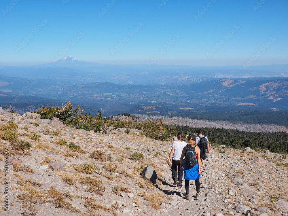 Hikers on the Timberline Trail on Mount Hood, Oregon, with distant views of Mount rainier and Mount Jefferson in the background on a very clear day.