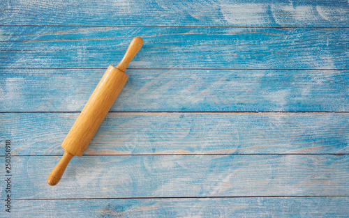 Wooden rolling pin on blue wooden table.