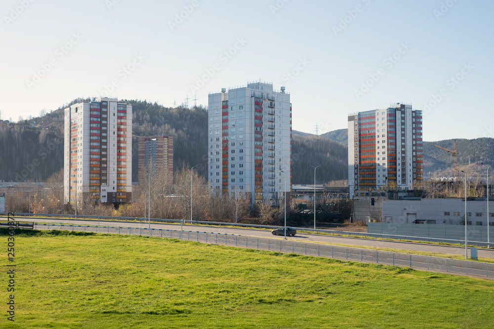 Urban area with residential buildings and the road against the background of a wooded mountain, in Krasnoyarsk in the autumn.