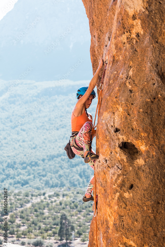 A girl in a helmet climbs a rock.