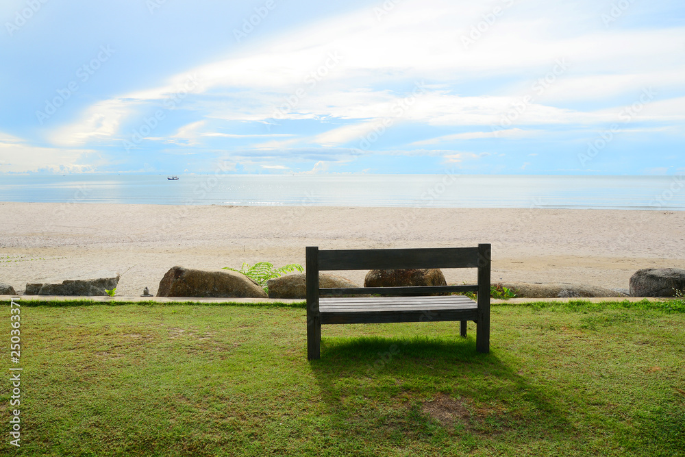 Empty wooden bench on the beach, looking into the wide and endless sea Empty wooden bench on the beach, looking into the wide and endless sea