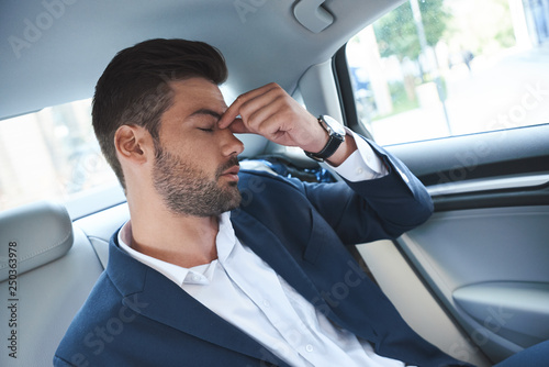 A young man is upset and sits in the gray cabin of a luxury car photo