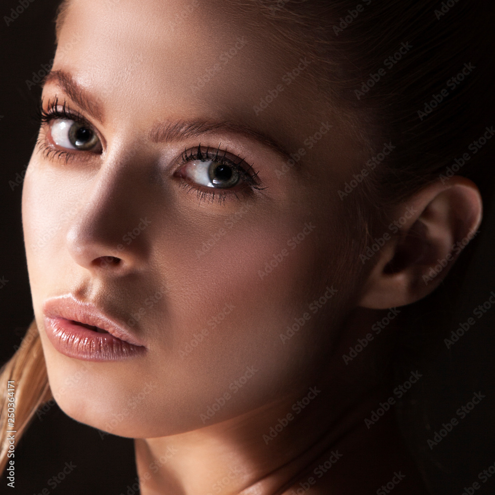 Fototapeta premium Girl beauty face close-up with clean skin, natural make-up, clean fresh skin, dark shadow portrait