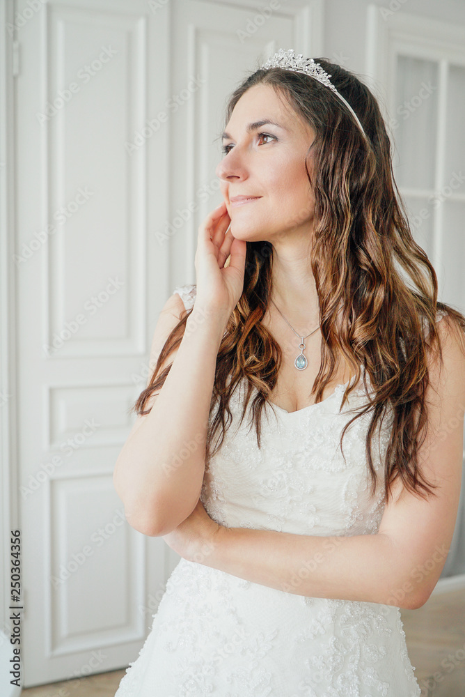 Beautiful smiling brunette woman bride in classical wedding dress in bright studio Beautiful smiling brunette woman bride in classical wedding dress in bright studio