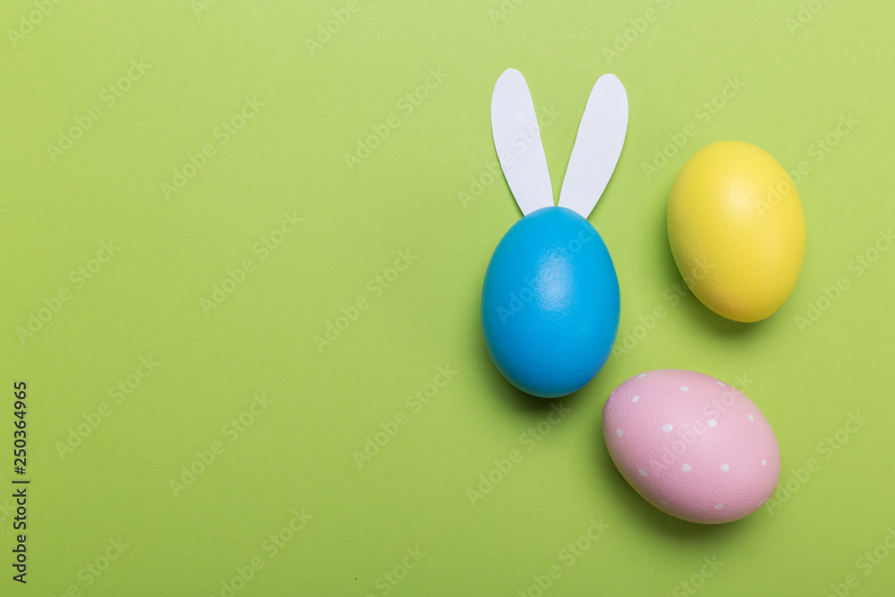 Colorfull easter eggs in nest on green pastel color background with space.