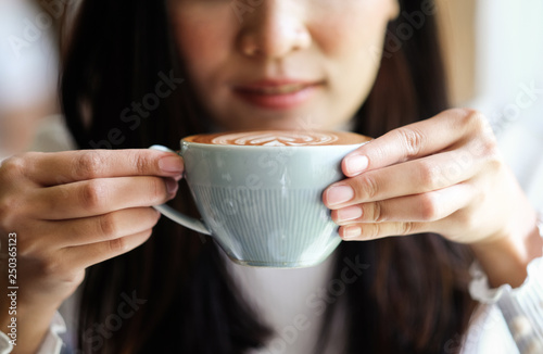 girl hand holding latte coffee in relaxing time of cafe 