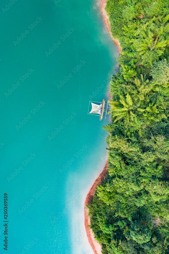 (View from above) Stunning aerial view of a a green coast of a tropical island with a traditional fishing boat in Nam Ngum Reservoir, Thalat, northern Laos.