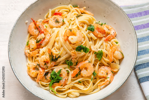 Linguine with shrimps on a rustic plate close-up, top view - traditional Mediterranean pasta with seafood, Italian cuisine..