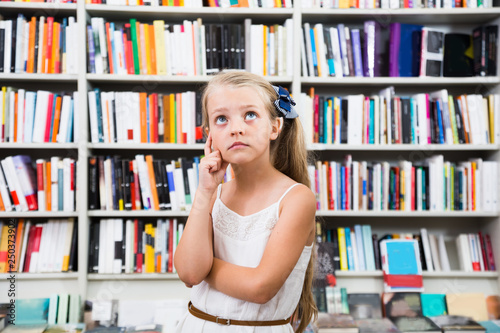 girl child puzzled of selection of books in the store