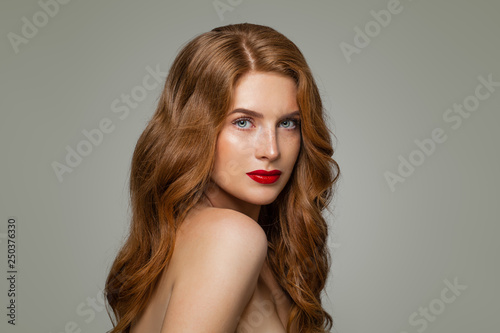 Portrait of woman with long curly beautiful ginger hair. Redhead girl