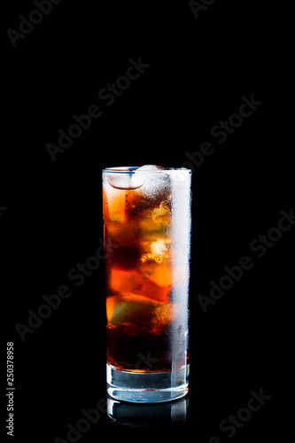 Cold cola beverage in glass with ice isolated on black background. Selective focus. Shallow depth of field.