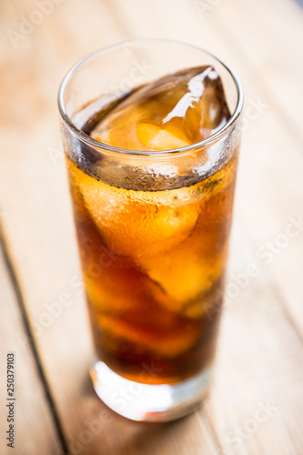 Cold cola beverage in glass with ice. Selective focus. Shallow depth of field.