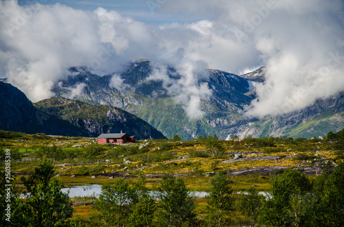 Red house and yellow meadow on Trolltunga trail in Norway