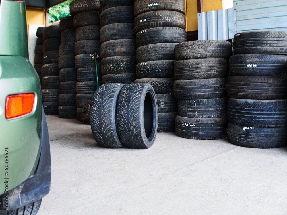 Used car tires stacked in piles at junkyard. Old wheels recycling and utilization concept. Tire Fitting Services Used car tires stacked in piles at junkyard. Old wheels recycling and utilization concept. Tire Fitting Services