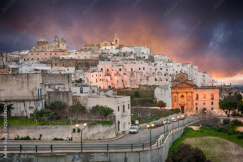 Panorama of The picturesque old town and Roman Catholic cathedral and church Confraternity of Carmine. The white city in Apulia on the hill - Ostuni , Puglia , Brindisi , Italy at sunset