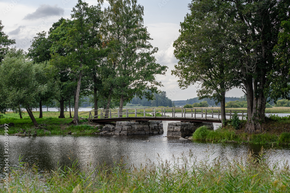Fototapeta premium Old narrow bridge with stone pillars ina green environment