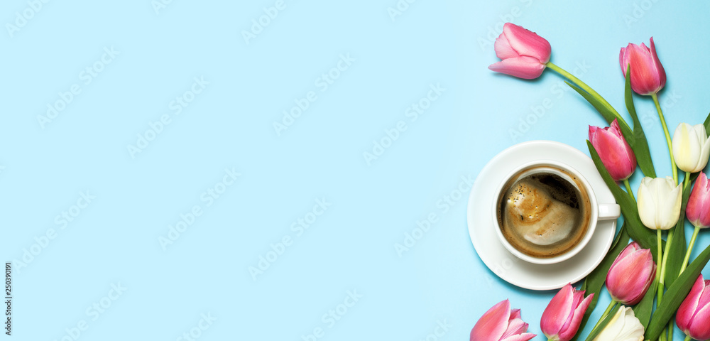 Minimalistc picture of cup of coffee and beautiful pink and white tulips on blue background. Spring breakfast concept. top view, flat lay. Copyspace for your text.