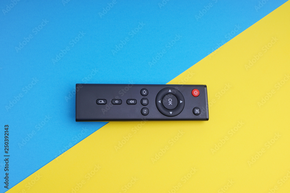 Fototapeta premium Remote control TV or radio on blue and yellow background with selective focus and crop fragment
