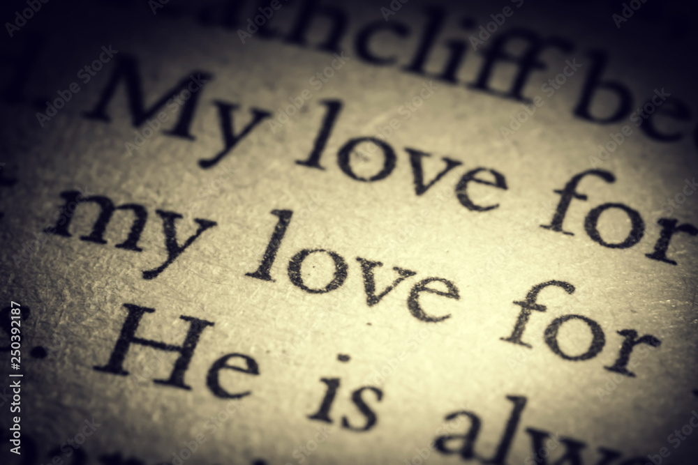 The word love on old page in a open book close-up macro. Vintage, grunge, old, retro style photo.