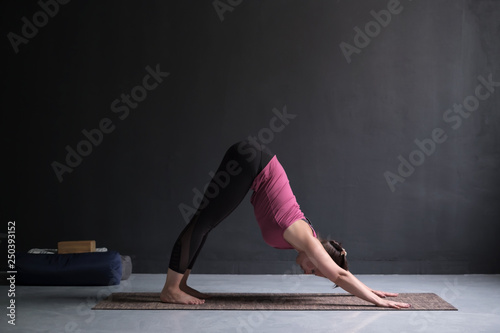 Woman doing yoga exercise downward facing dog pose, adho mukha svanasana