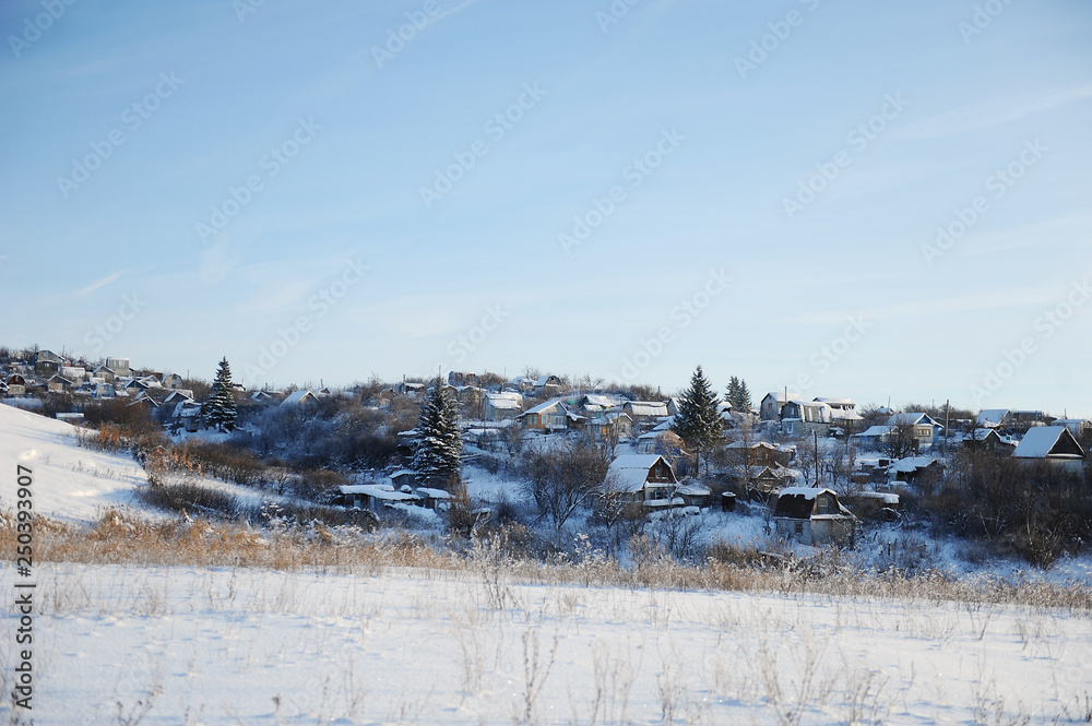 Winter snow landscape. Winter Russian village. Houses and trees. Bright blue sky