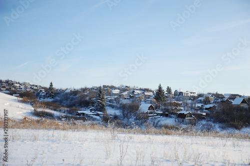 Winter snow landscape. Winter Russian village. Houses and trees. Bright blue sky