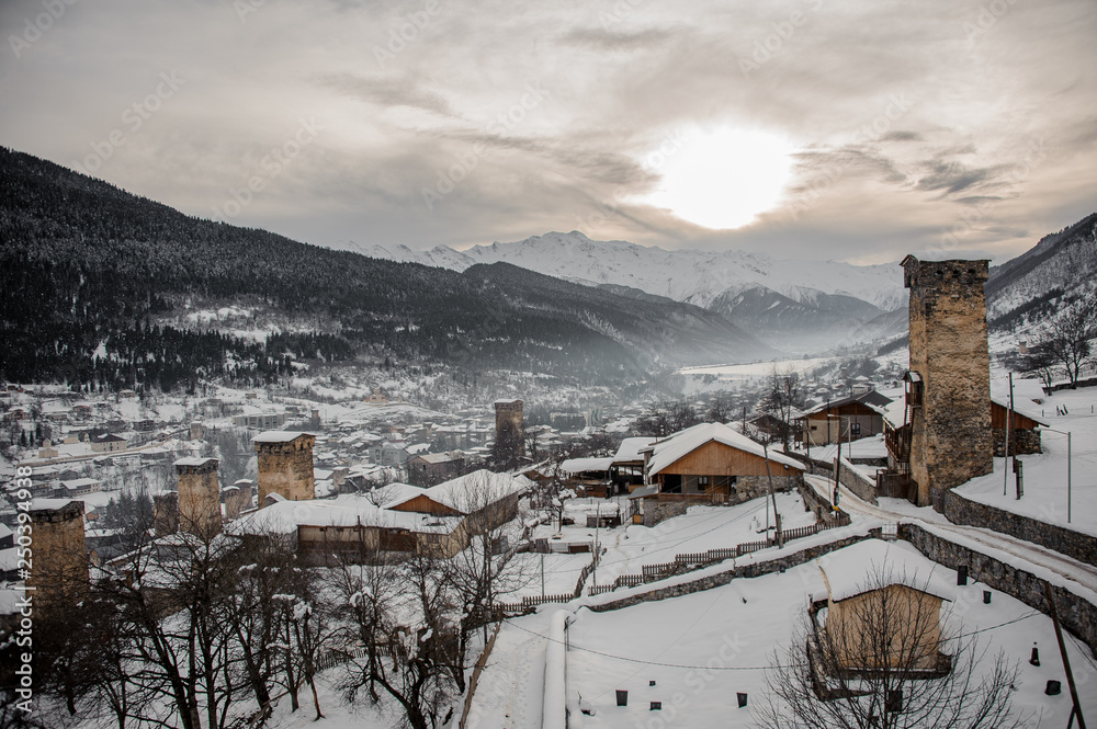 GEORGIA, SVANETI, MESTIA - JANUARY 30, 2019: View from above on the snow covered town with tower under the sun