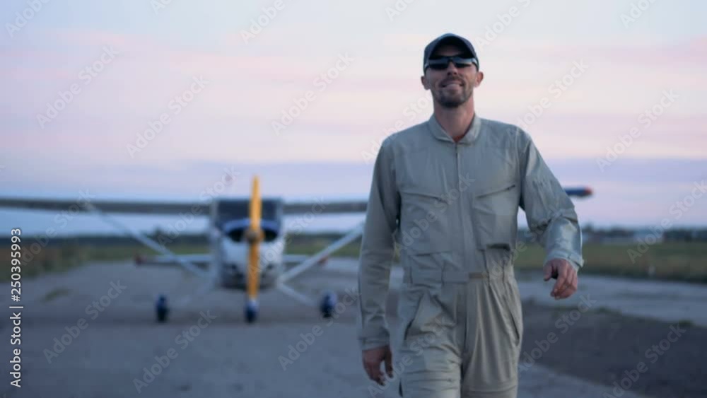 One pilot walks on a runways on a plane background, close up. One pilot walks on a runways on a plane background, close up.