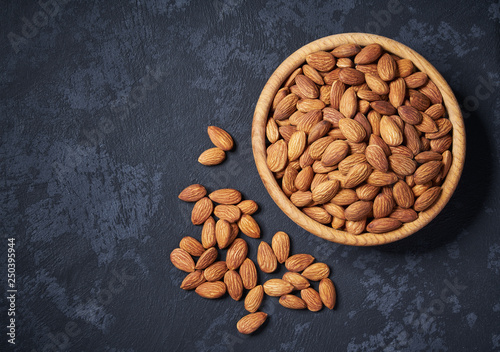 Almond in wooden bowl on black background with copy space.Flat lay