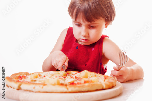 Cute little girl with pizza. Happy child having fun eating dinner.