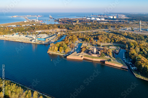 Medieval Wisloujscie Fortress with old lighthouse tower in port of Gdansk, Poland. A unique monument of the fortification works. Aerial view at sunset. Exterior Northern Gdansk port in the background