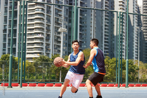 young asian adult men playing basketball on outdoor court © imtmphoto