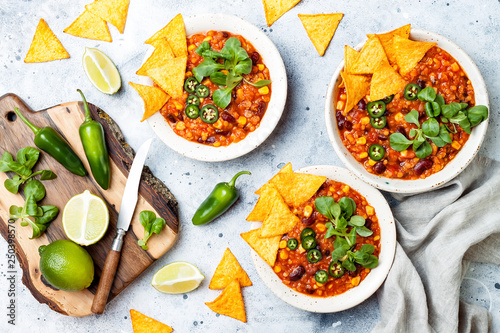 Vegetarian chili con carne with lentils, beans, nachos, lime, jalapeno. Mexican traditional dish