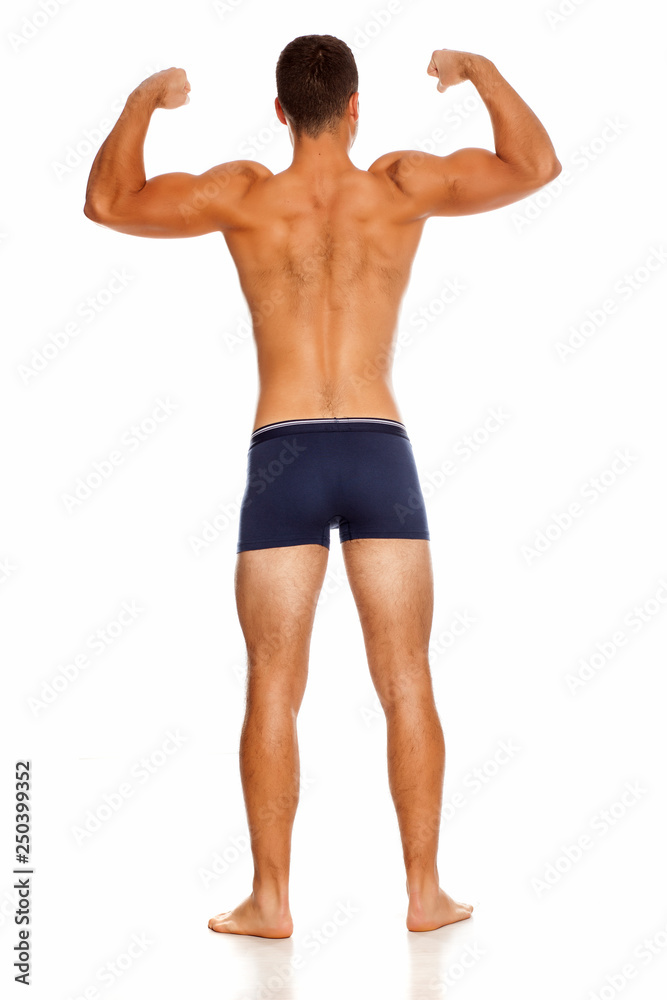 Back view of shirtless handsome man in panties on white background showing his biceps