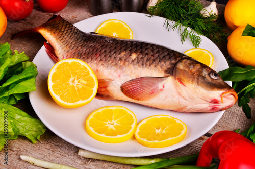 Fresh Cyprinus carpio carpio fish on wooden cutting board with tomatoes