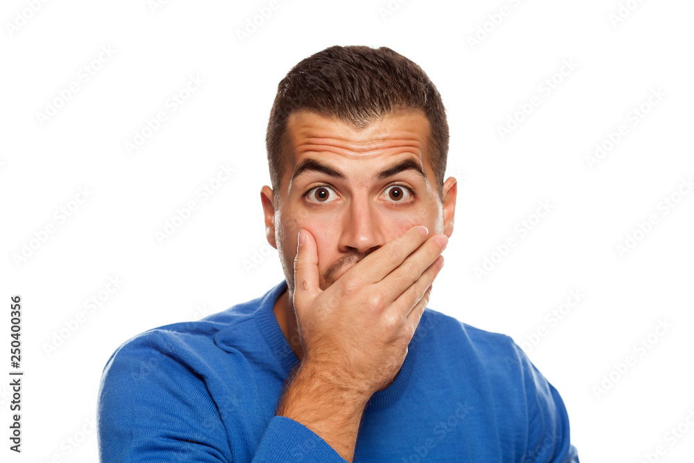 Portrait of young shocked man on white background