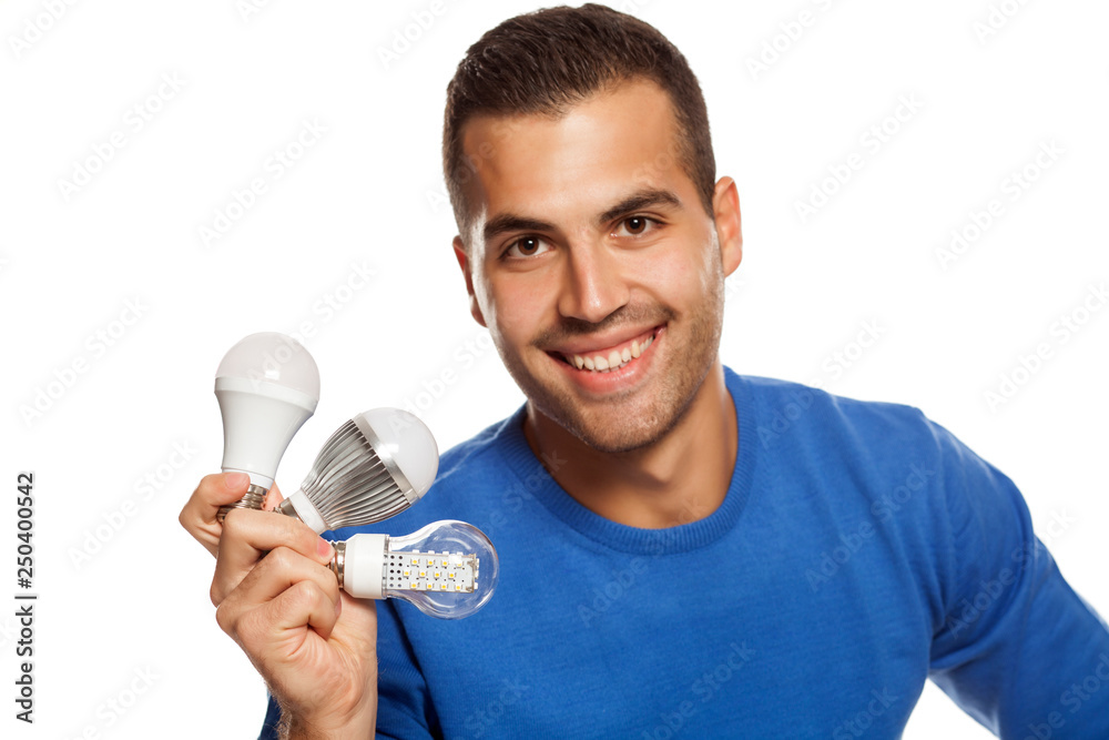 portrait of happy young man, holding three different LED bulbs on white background portrait of happy young man, holding three different LED bulbs on white background