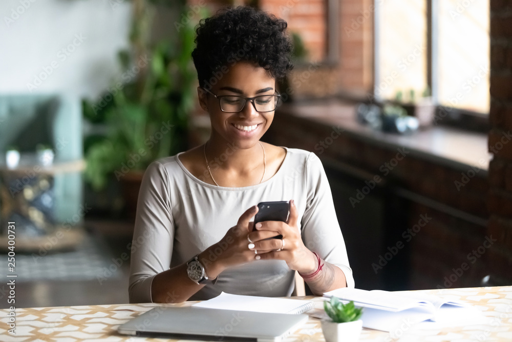 Fototapeta premium Black woman sitting at table take a break surfing internet