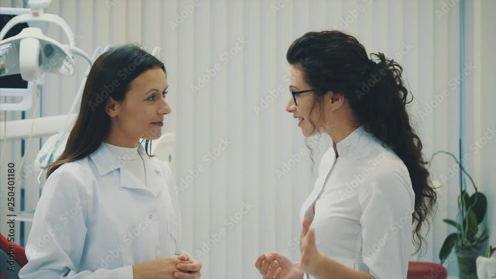 Two doctor dentist in the office. Beautiful young women. Stand and talk dressed in medical white clothes. Two doctor dentist in the office. Beautiful young women. Stand and talk dressed in medical white clothes.