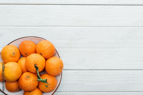 top view of ripe orange tangerines in plate on wooden white background