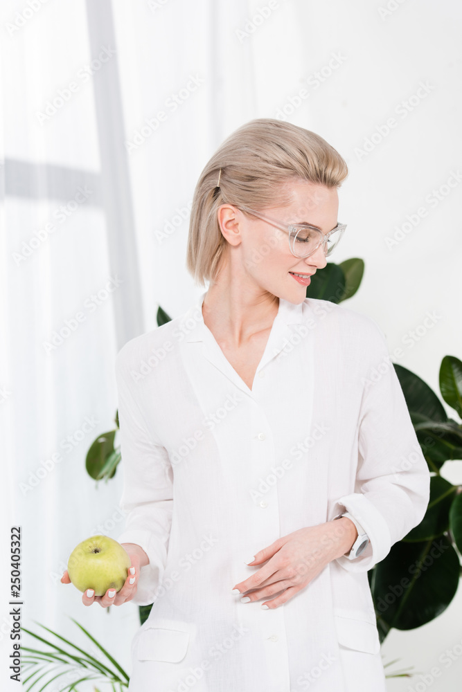 cheerful businesswoman in glasses holding green apple in office cheerful businesswoman in glasses holding green apple in office