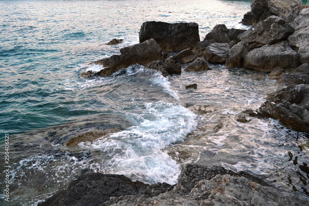Wild sea panorama surrounded with sharp rock stones in summer on sunny sunset day. Beauty and force of deep water. Danger o swimming in forbidden places. Wild sea panorama surrounded with sharp rock stones in summer on sunny sunset day. Beauty and force of deep water. Danger o swimming in forbidden places.